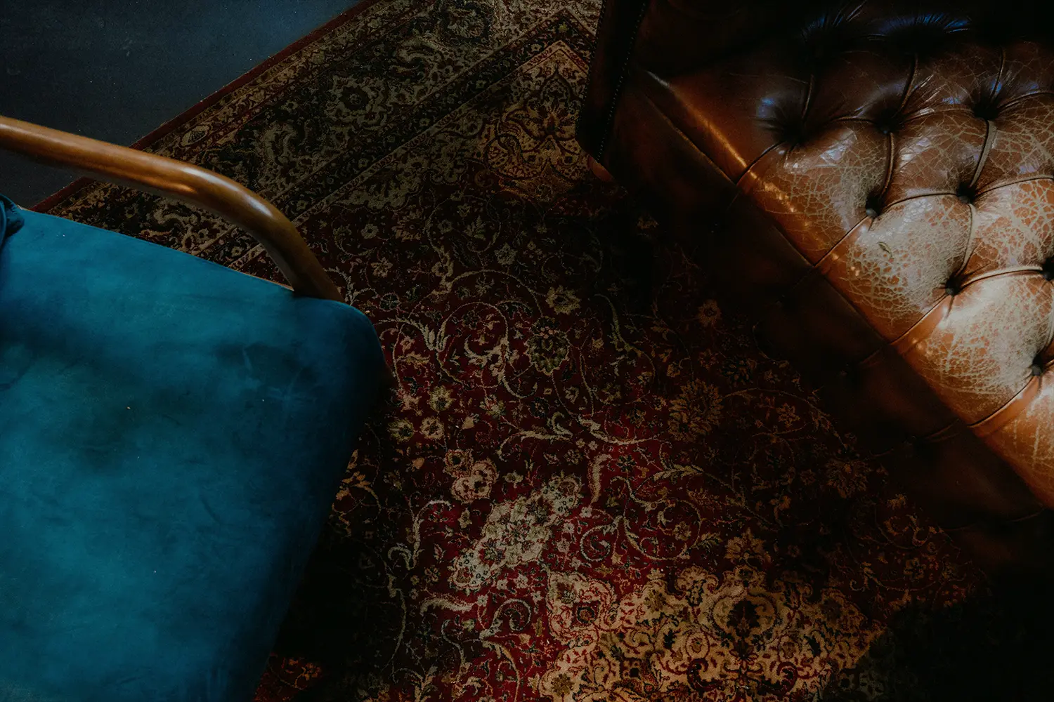 Detailed corner of a tufted leather chair on a hand-knotted rug